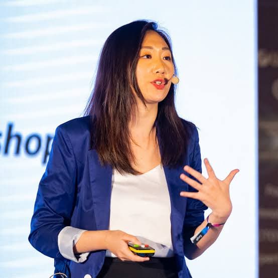 Sharon Gai speaking on stage at a conference
