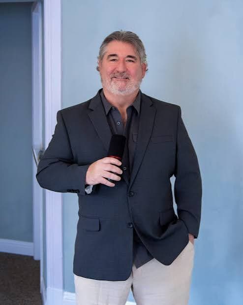 Steve Ramona holding a microphone, host of Doing Business with a Servant's Heart